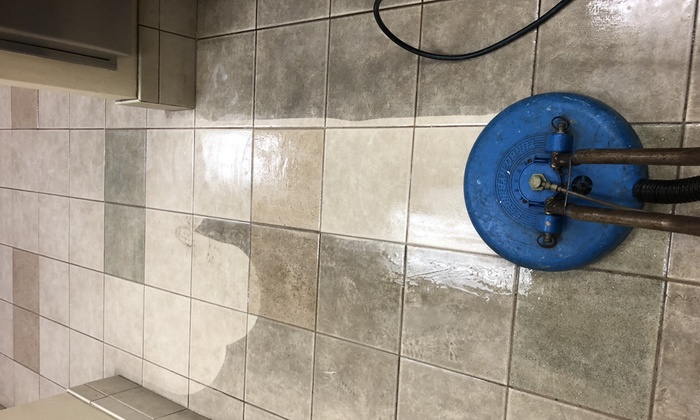 A technician applying protective sealing to freshly cleaned grout lines in a modern kitchen.